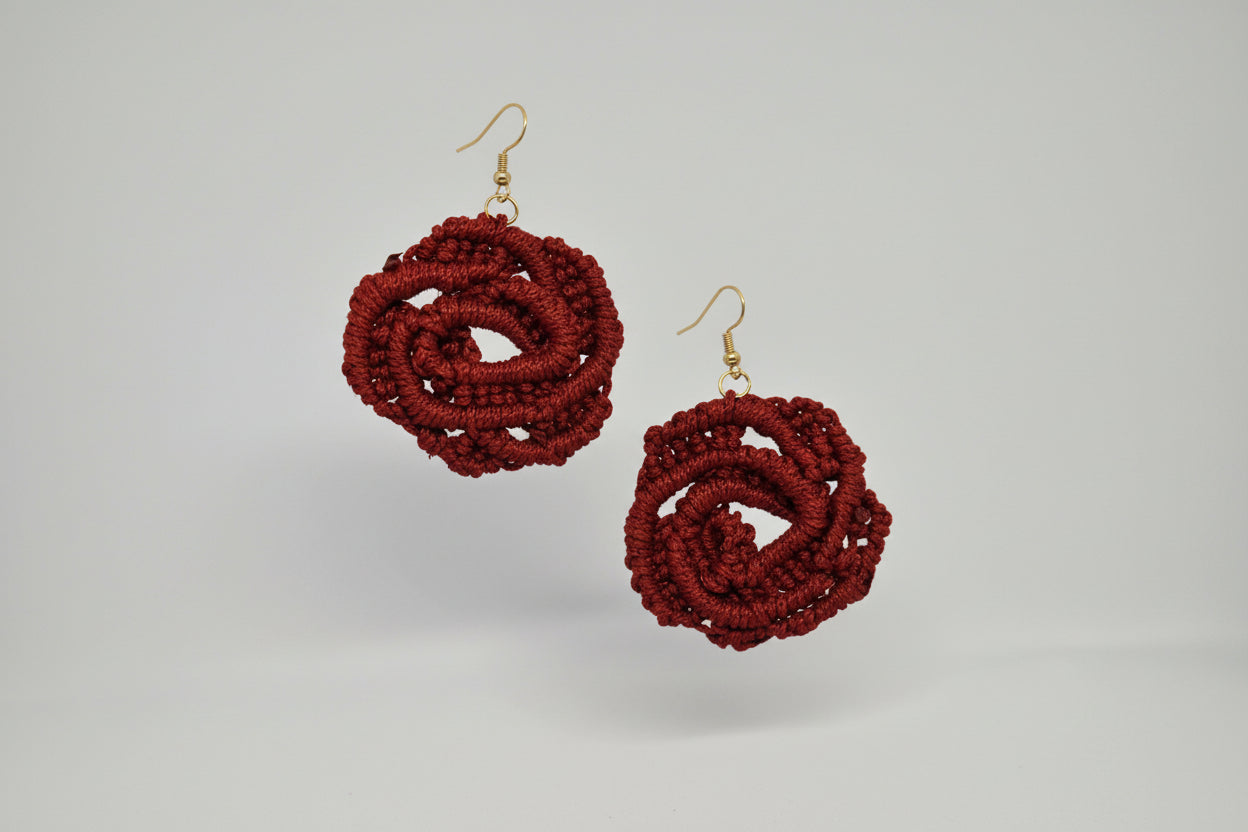 Red crochet earrings on a white card with a gray background