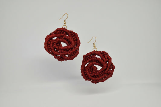 Red crochet earrings on a white card with a gray background