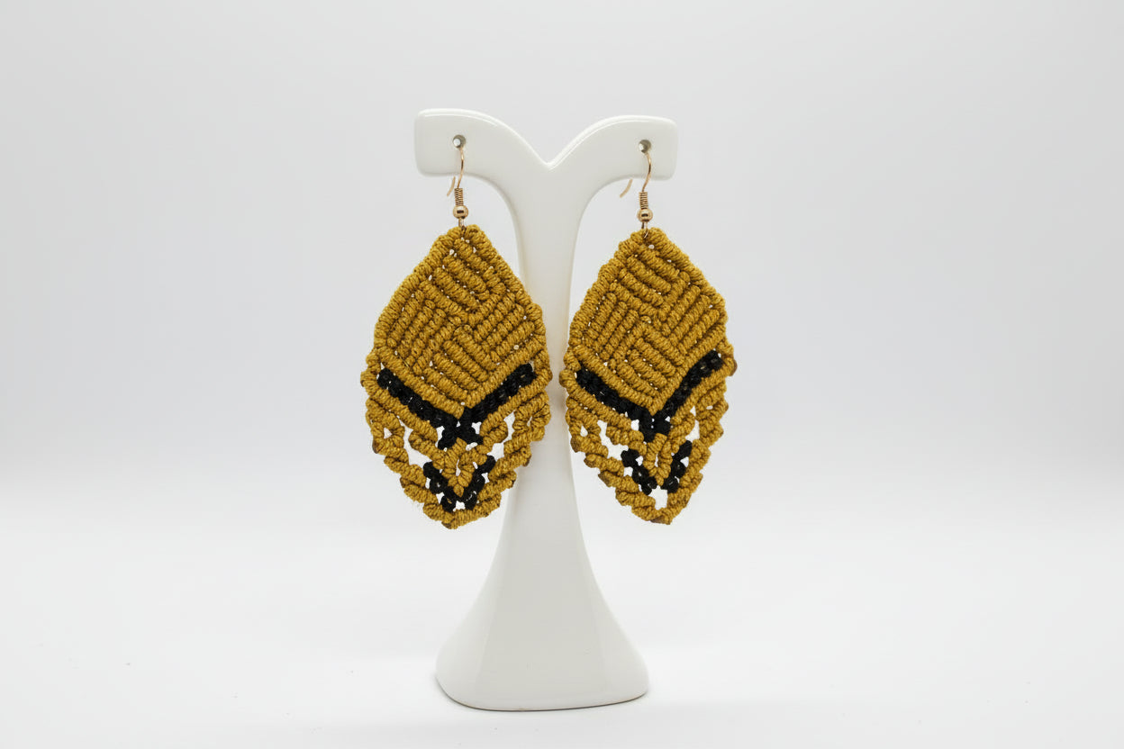 Pair of gold and black beaded earrings on a gray background